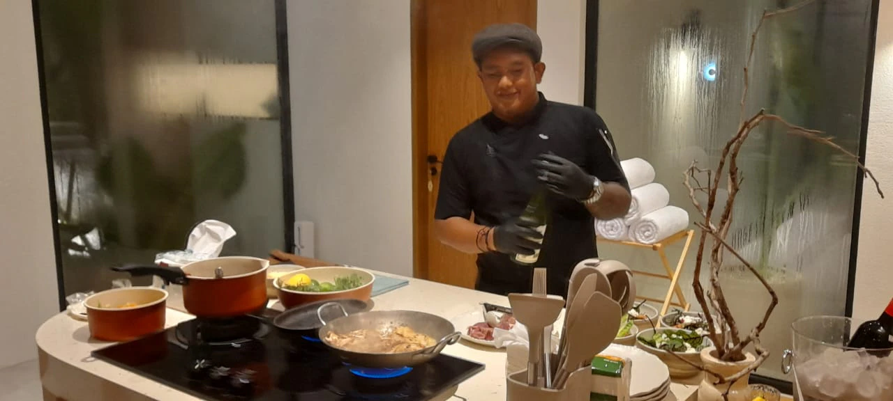 Chef Galung smiling while cooking in a villa kitchen at night