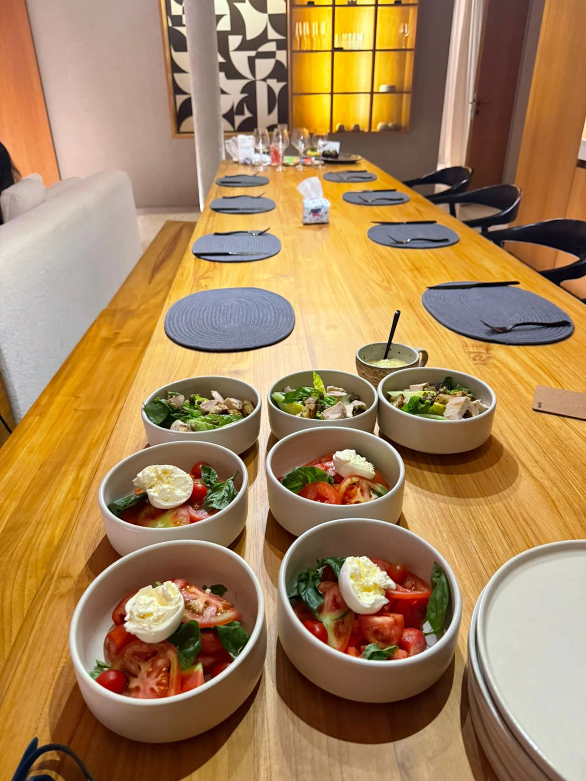 Bowls of caprese and chicken salad set along a long villa dining table