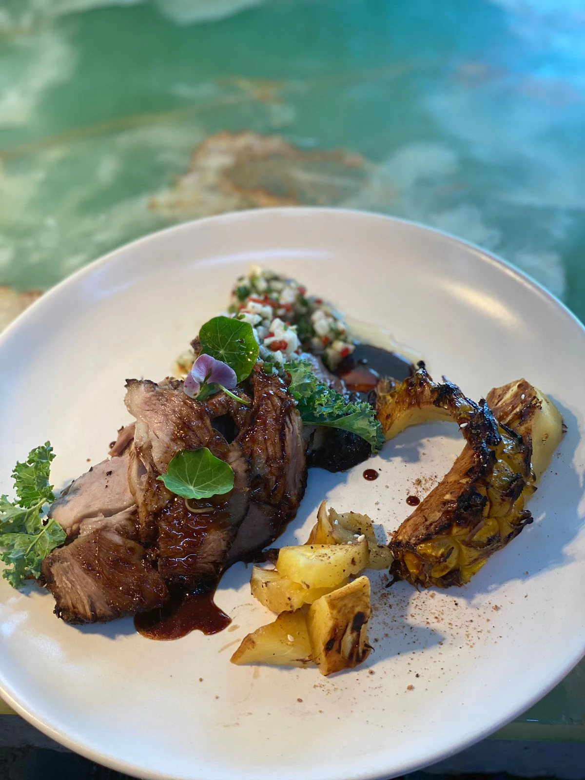 Glazed pork belly plated with grilled pineapple and salsa
