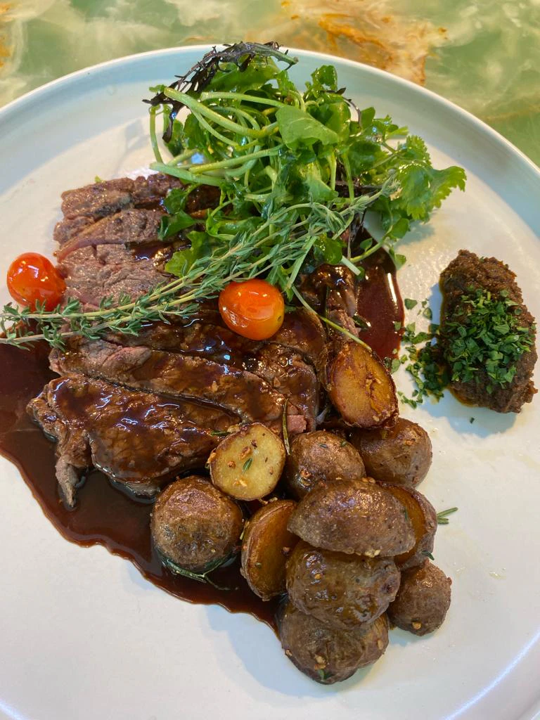 Sliced steak with red wine sauce, baby potatoes and fresh herbs