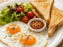 Two fried eggs with toast, fresh salad, potato and Balinese chilli dip